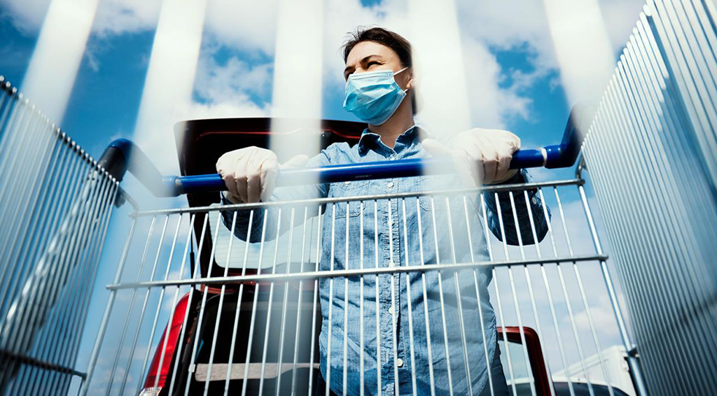 A man wearing a mask and pushing a shopping cart